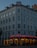 A multi-story building with intricate architectural details, featuring arched windows and decorative molding. The ground floor houses a restaurant named Floras Steakhouse, illuminated with neon red lights and warm string lights around the entrance.
