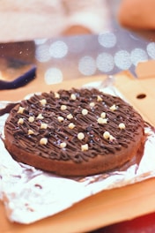 A chocolate cookie with white sprinkles on a piece of aluminum foil