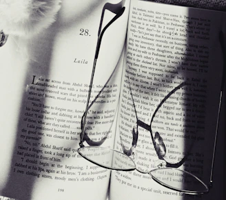 An open e-book showing a page of a thrilling mystery novel with a magnifying glass beside it.