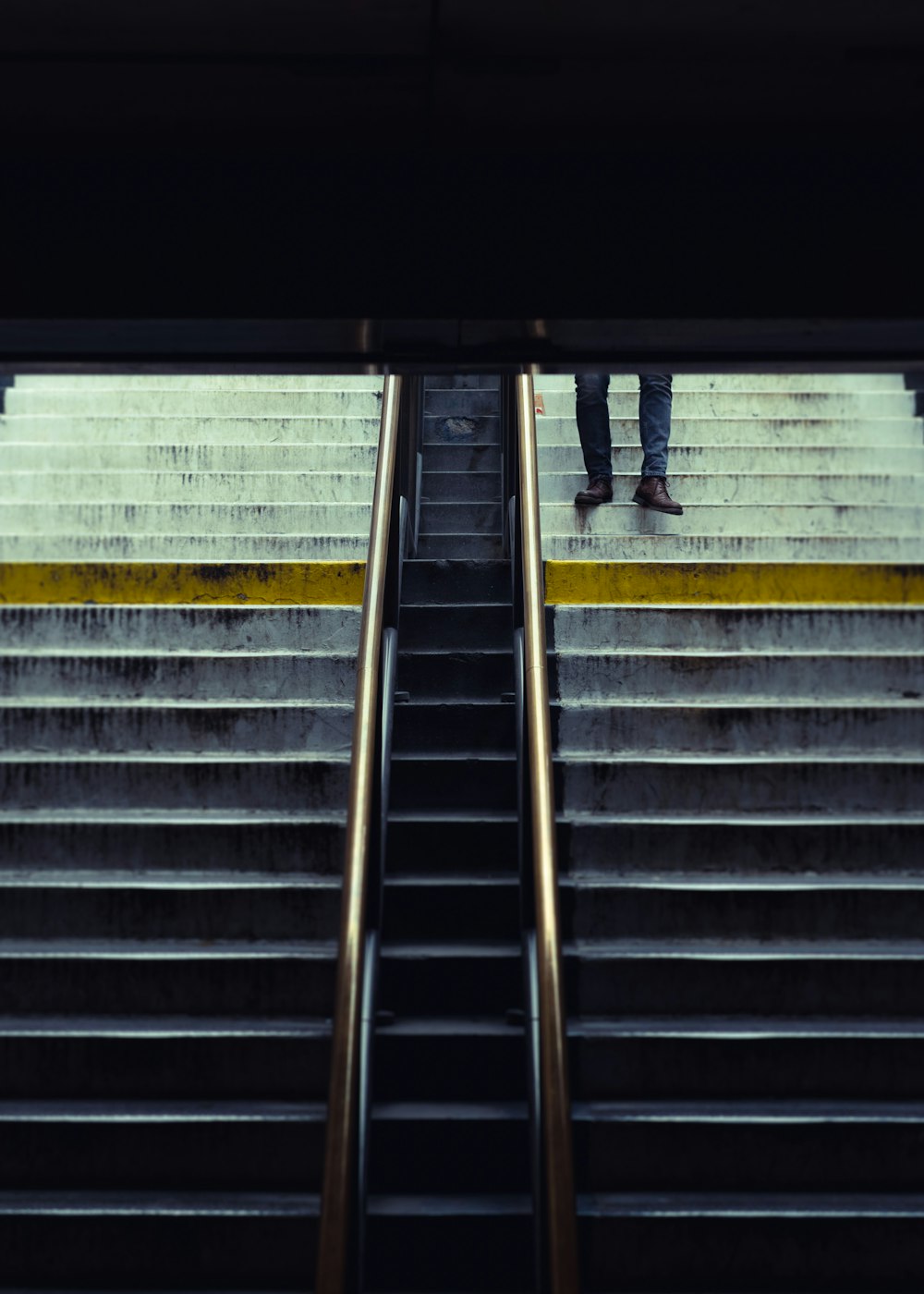 Persona in pantaloni neri che cammina su scale di cemento grigio