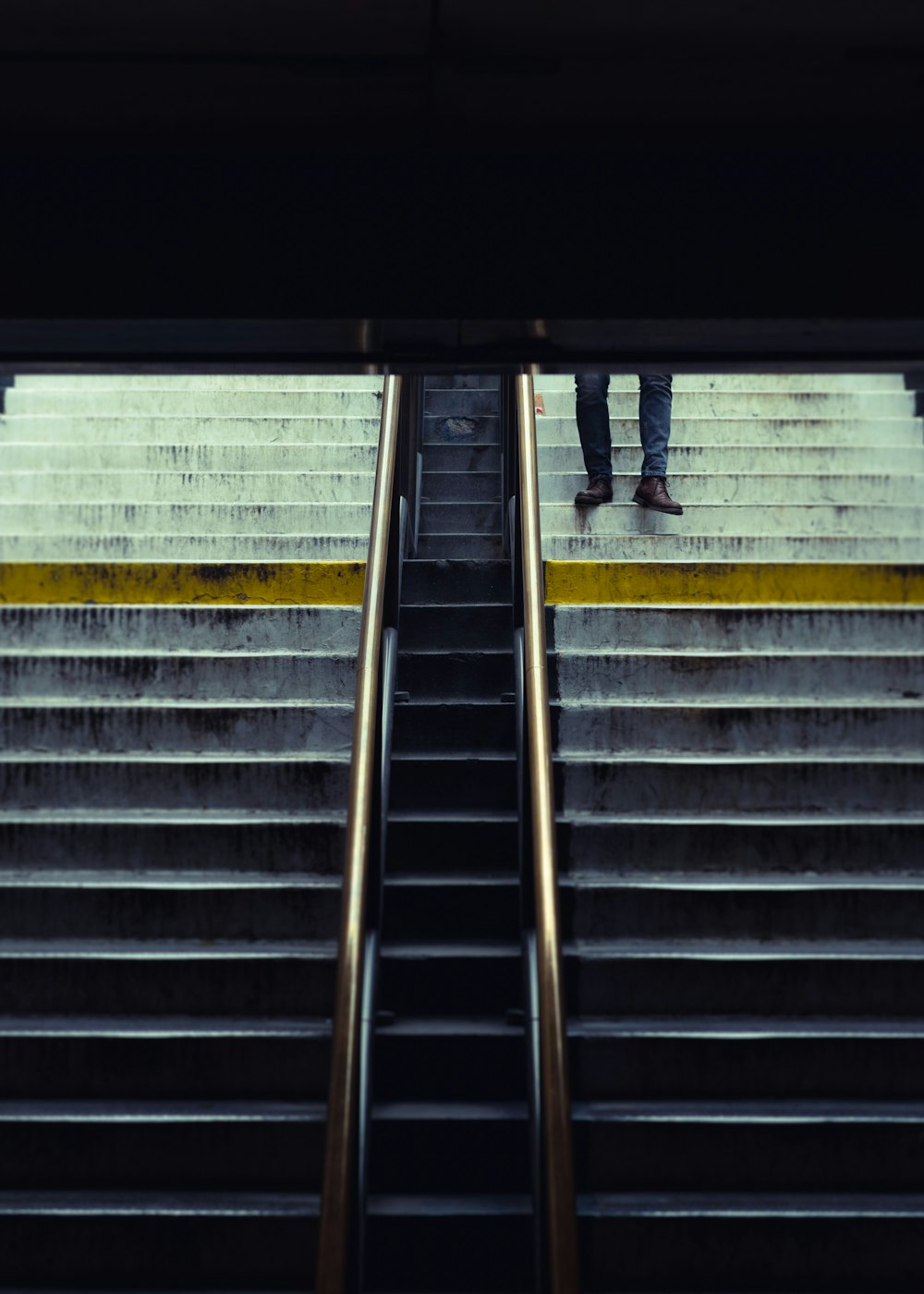 personne en pantalon noir marchant sur des escaliers en béton gris