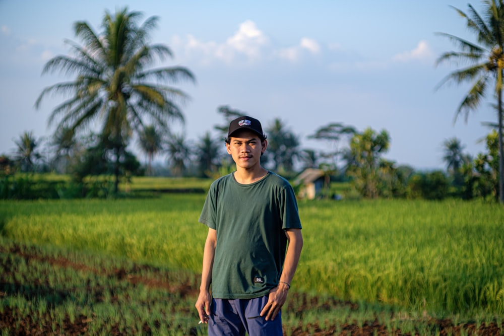 man in green crew neck t-shirt standing on green grass field during daytime