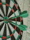 green darts hitting bullseye on dartboard