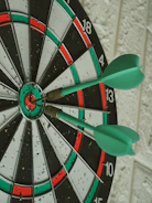 green darts hitting bullseye on dartboard