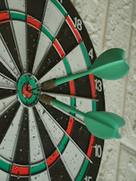 green darts hitting bullseye on dartboard