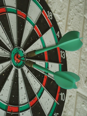 green darts hitting bullseye on dartboard