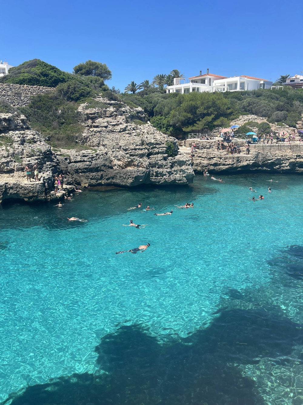 pessoas nadando no mar perto da montanha rochosa durante o dia