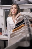 A woman smiling while looking at her wardrobe filled with clothes.