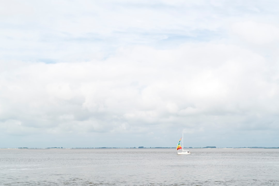 white sailboat on sea under white clouds during daytime