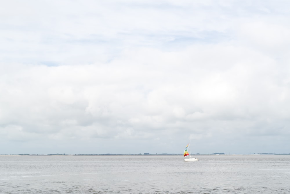 white sailboat on sea under white clouds during daytime