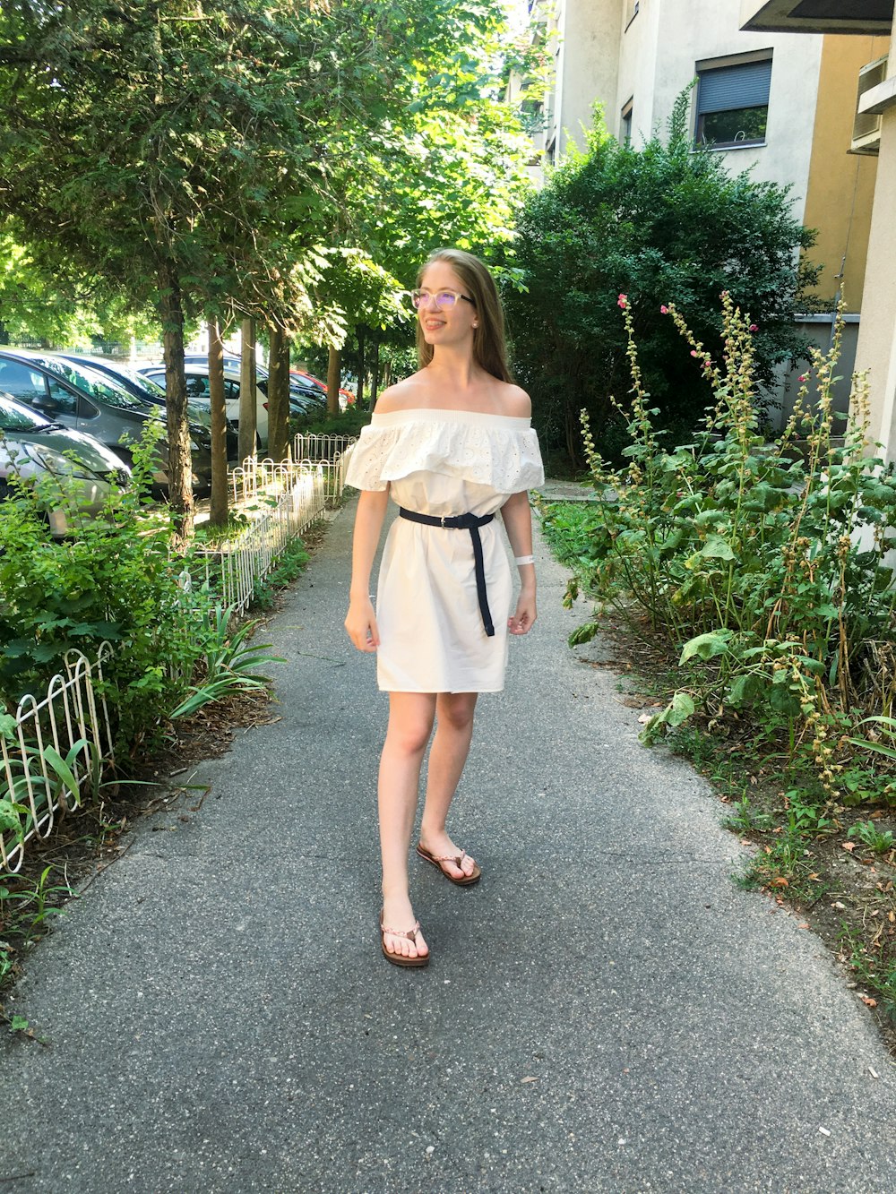 歩道に立つ白いドレスの女性