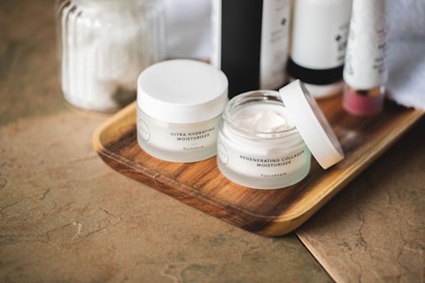 Flat lay of gentle skincare products including cleanser, sunscreen, serum, and moisturizer on a neut