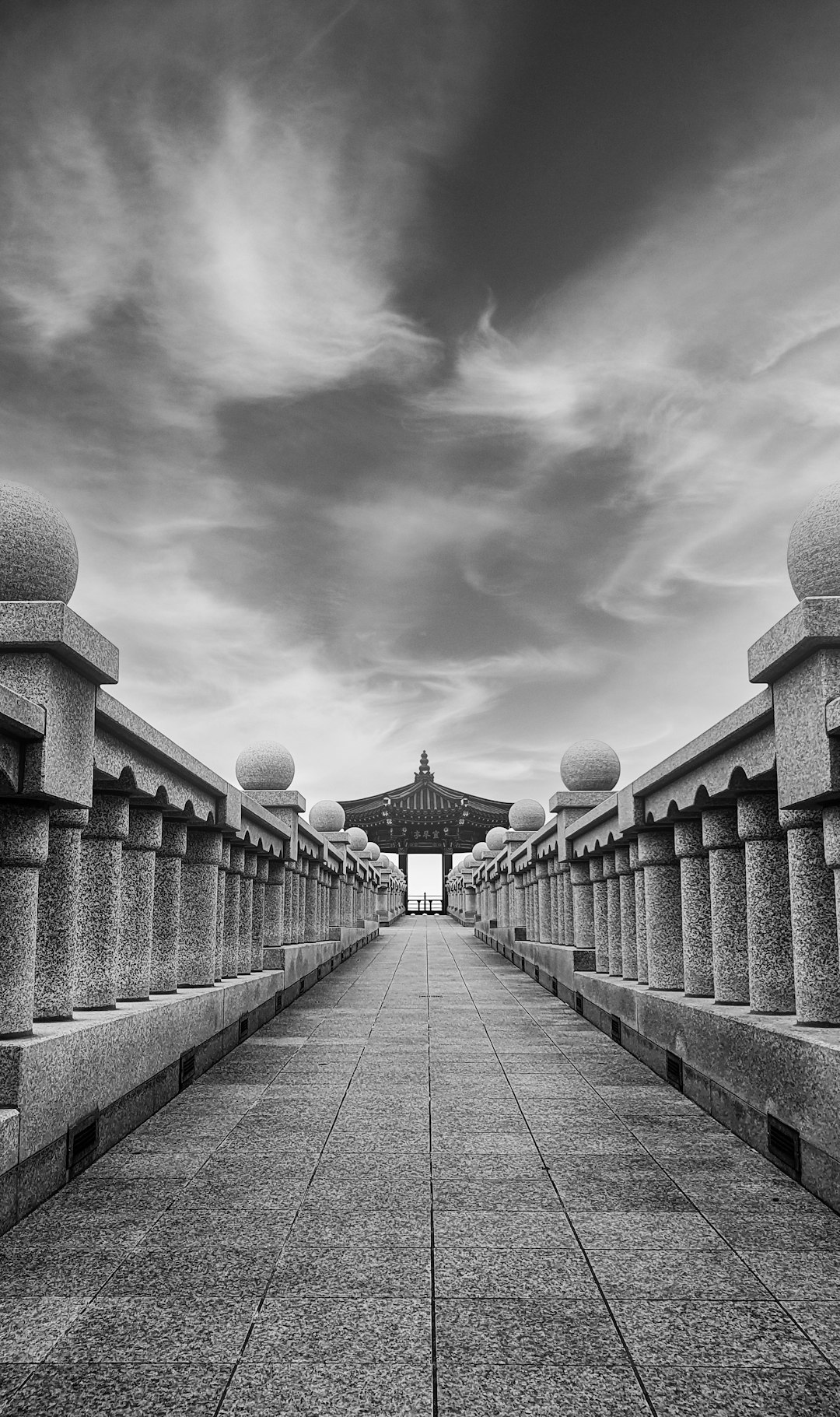 grayscale photo of bridge with people walking on it