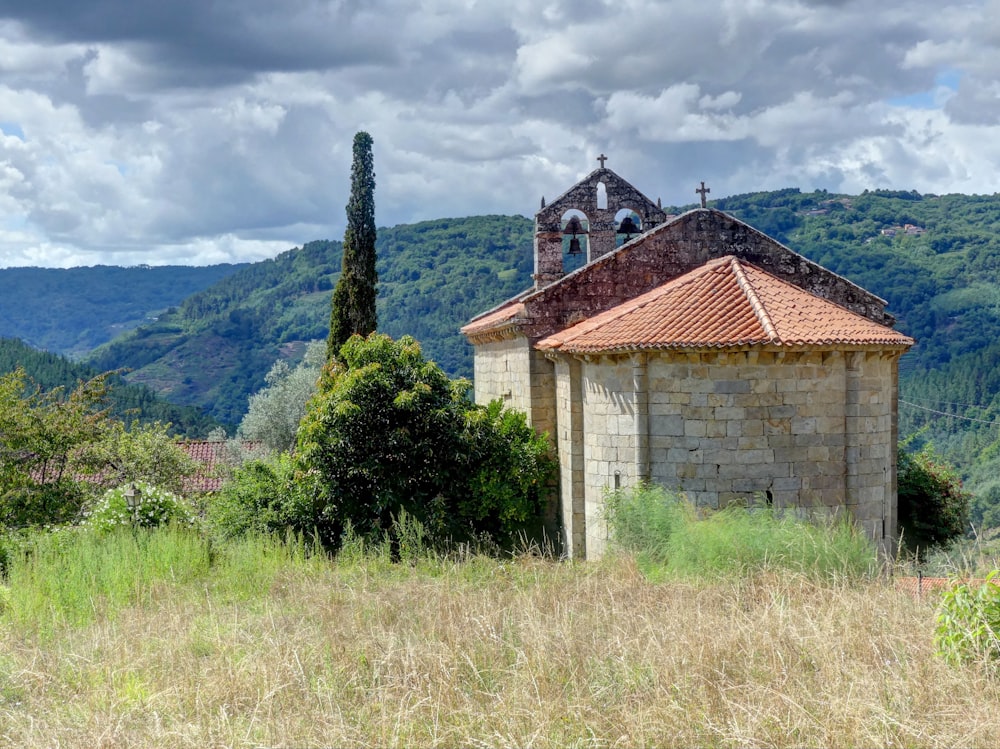 brown and white concrete house near green trees and mountain during daytime