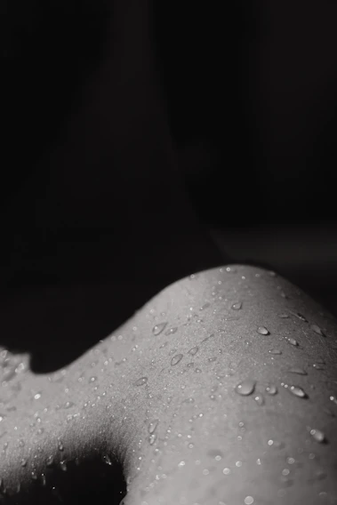 Close-up of dewy skin with water droplets catching soft natural light.