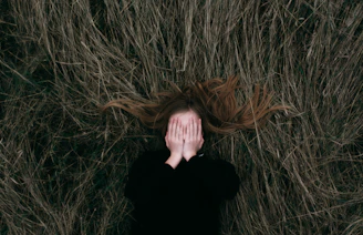 woman in black long sleeve shirt lying on brown grass field