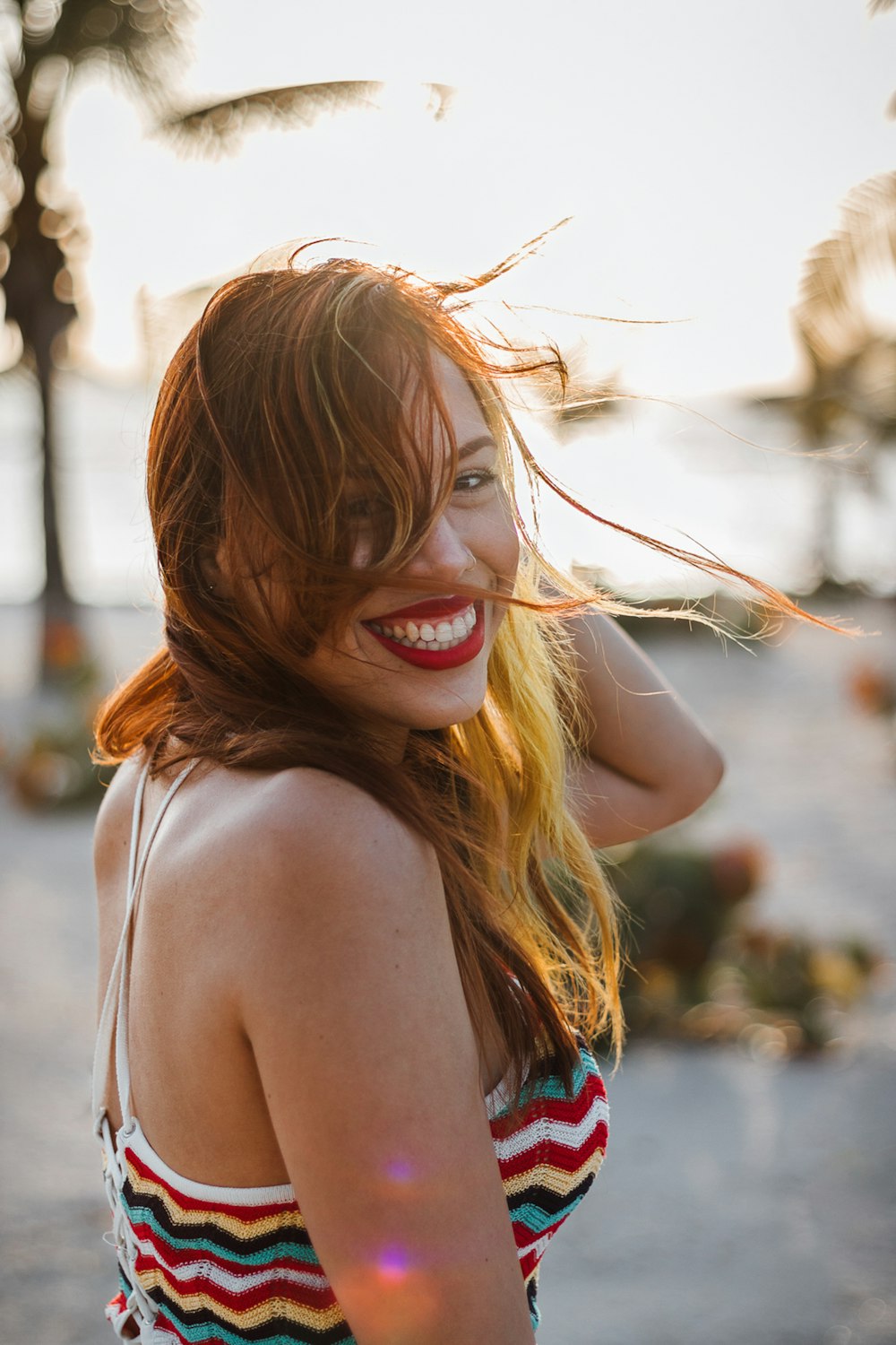 smiling woman in blue and red tank top wearing brown framed eyeglasses