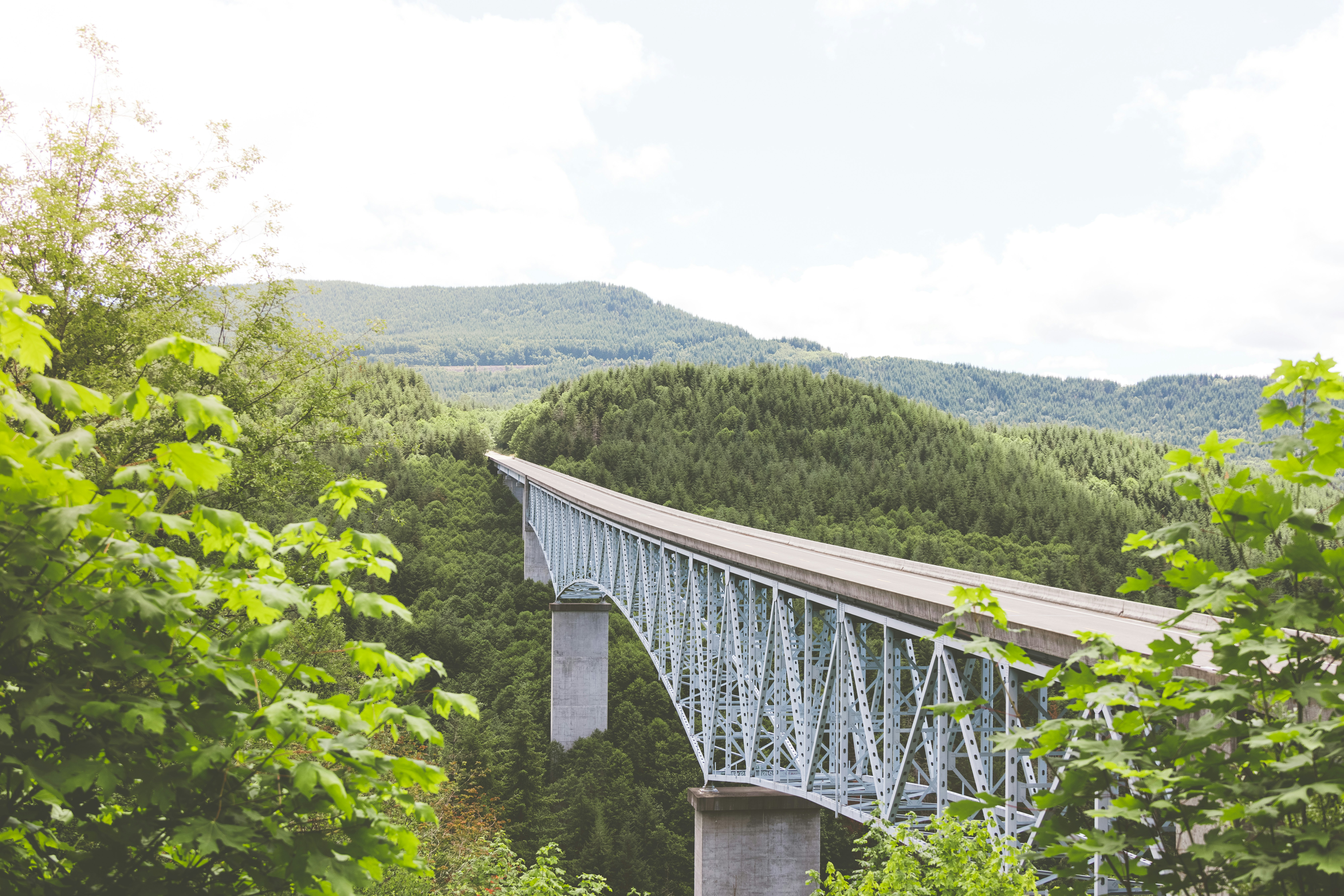 gray metal bridge over green mountains during daytime