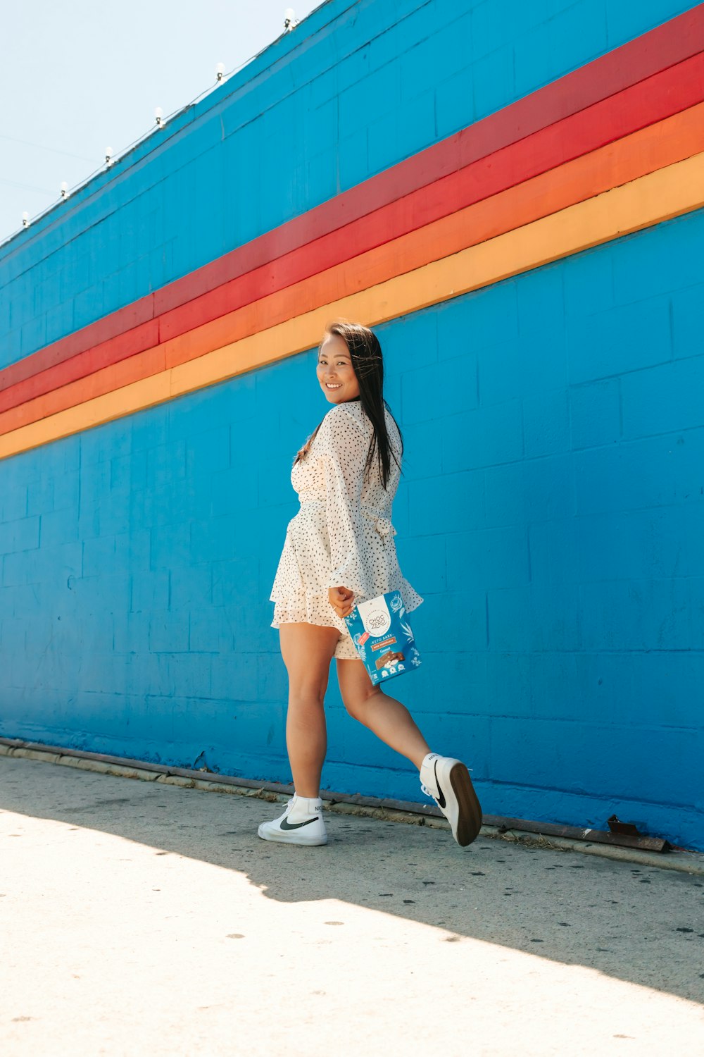 mujer con camisa de vestir a cuadros azules y blancos y pantalones cortos de mezclilla azules de pie junto a azul y