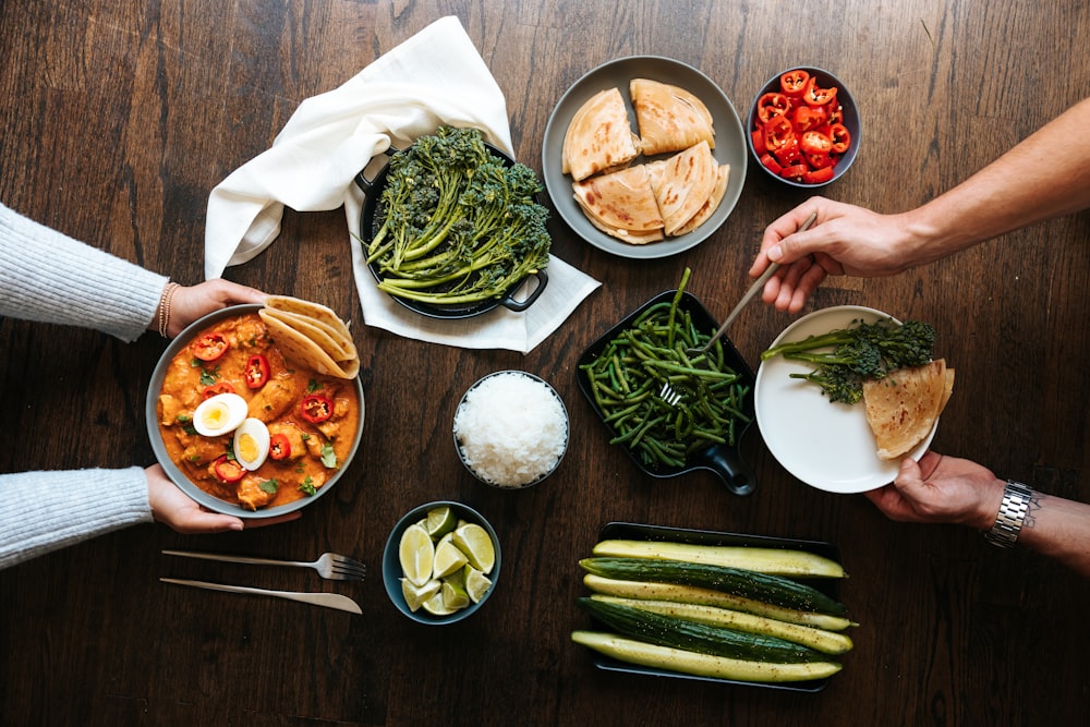 person holding green vegetable and white ceramic bowl with soup