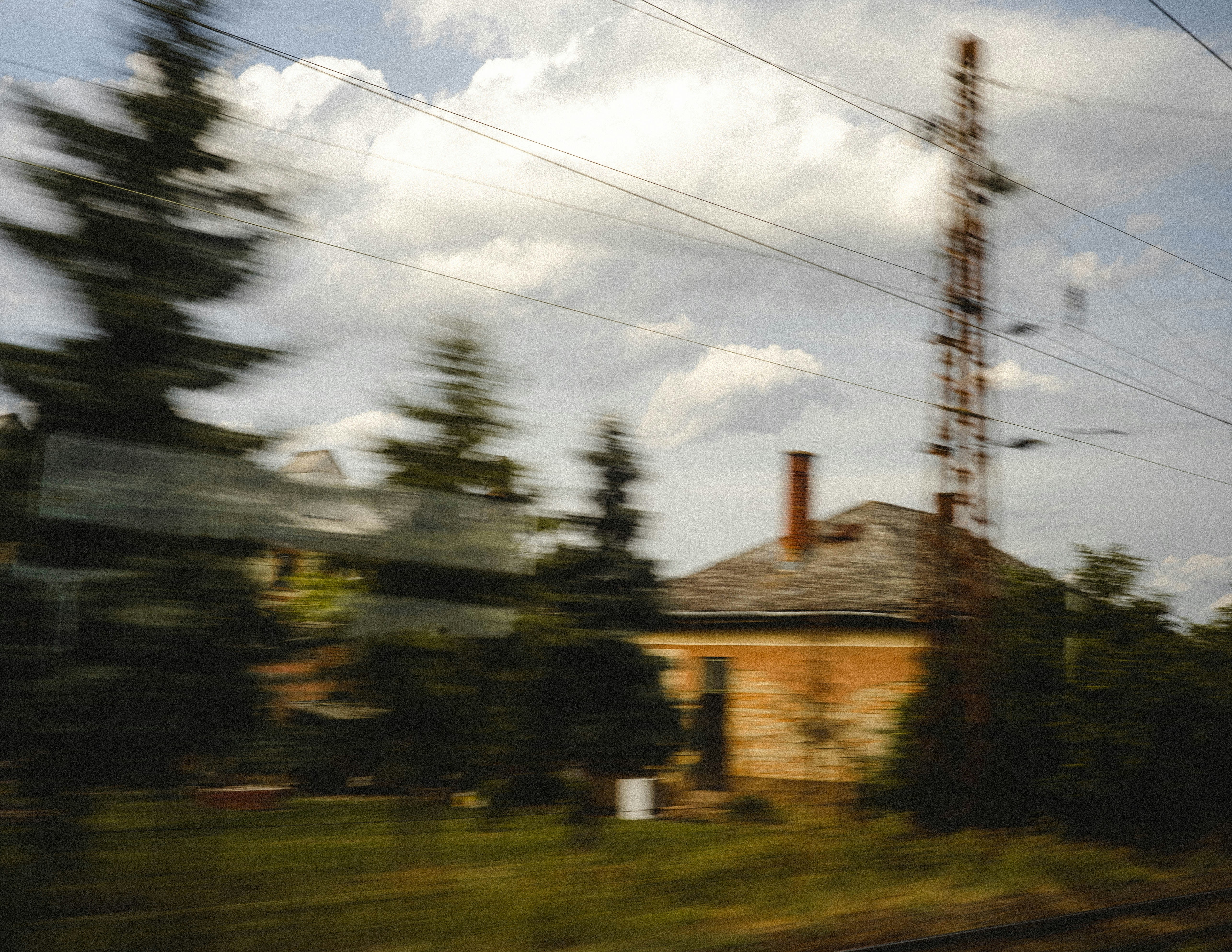 brown and white house near green trees under white clouds and blue sky during daytime