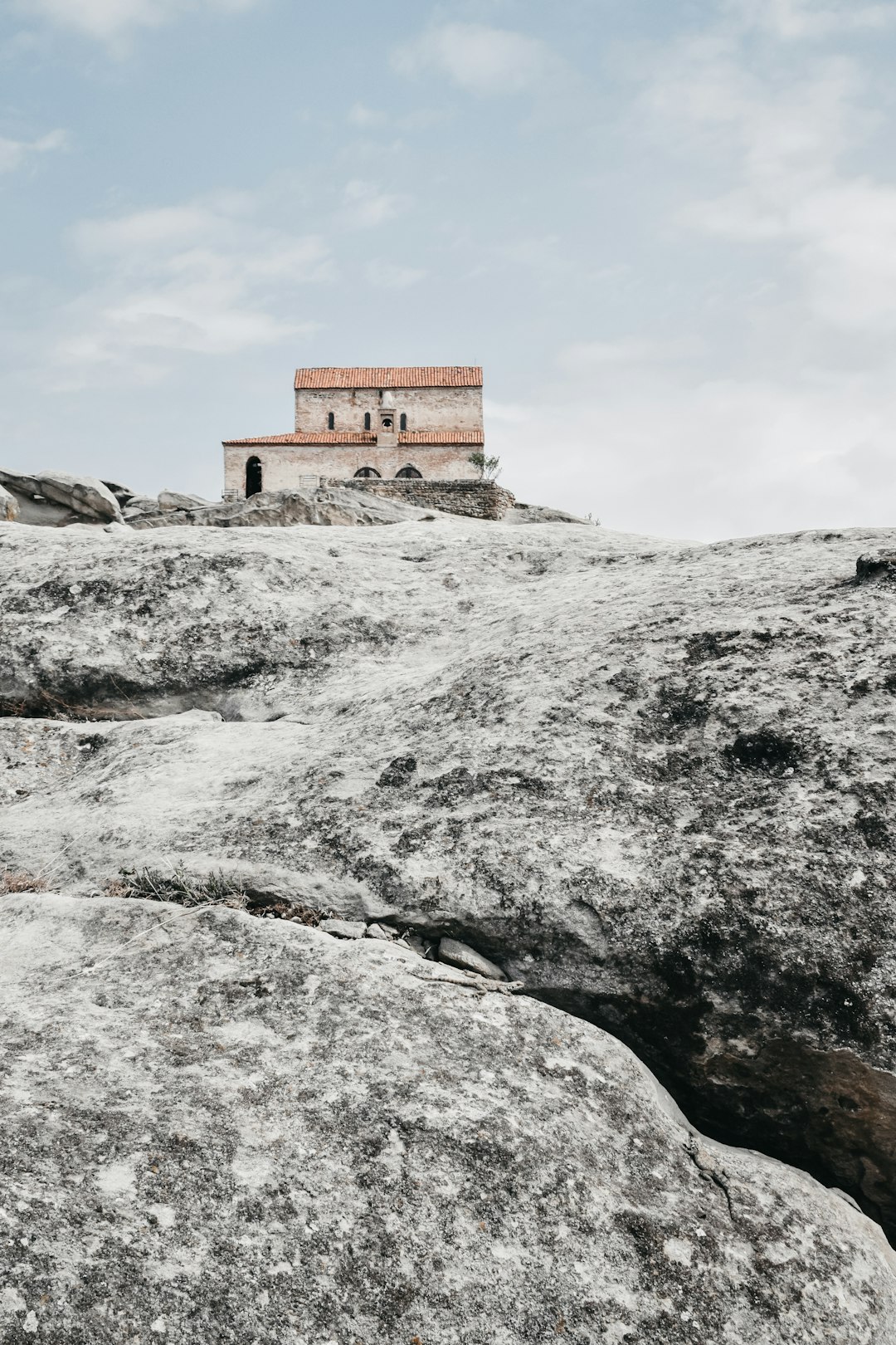 brown concrete building on gray rocky hill under white clouds during daytime