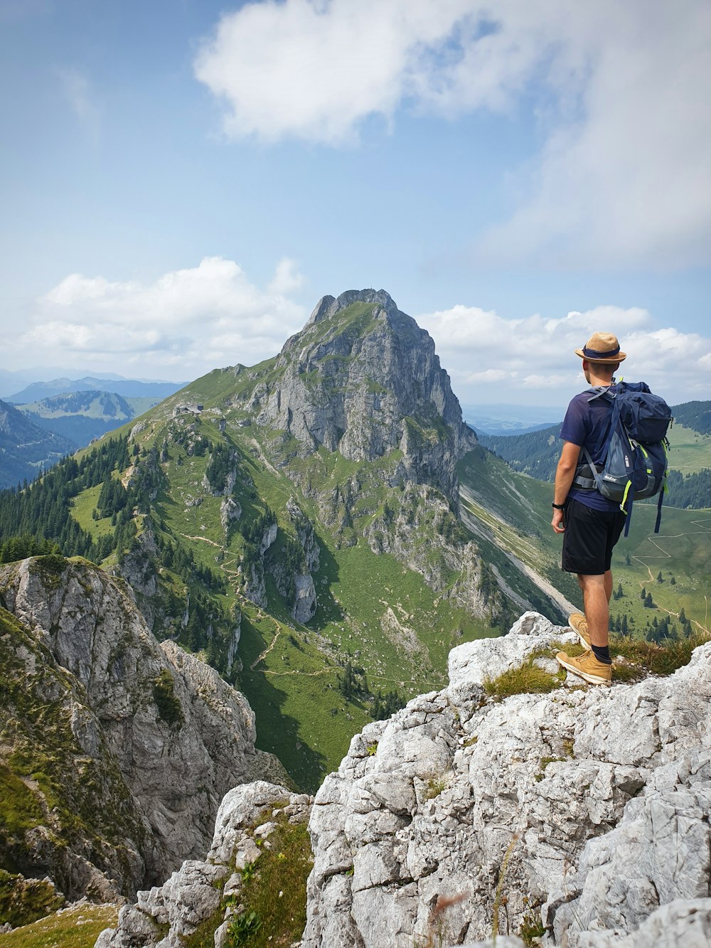 homme en chemise noire et short en jean bleu debout sur rock mountain pendant la journée