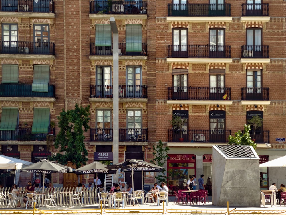 people sitting on white chairs near brown concrete building during daytime