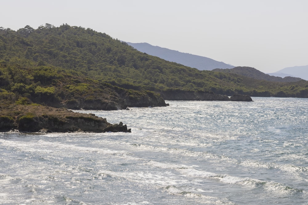 green mountain beside body of water during daytime