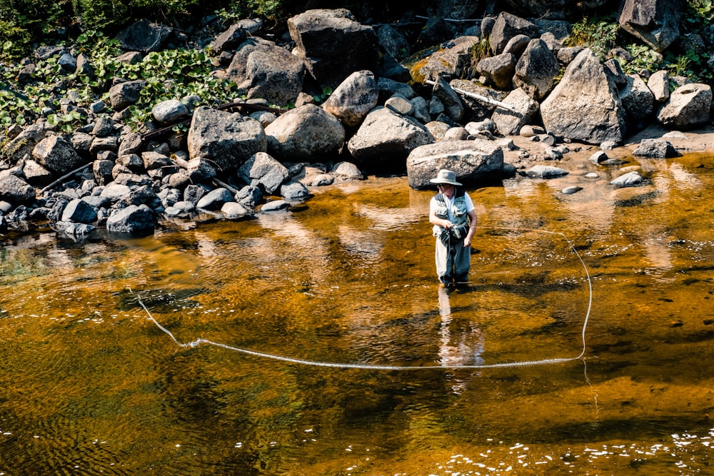 man in black jacket and black pants fishing on river during daytime