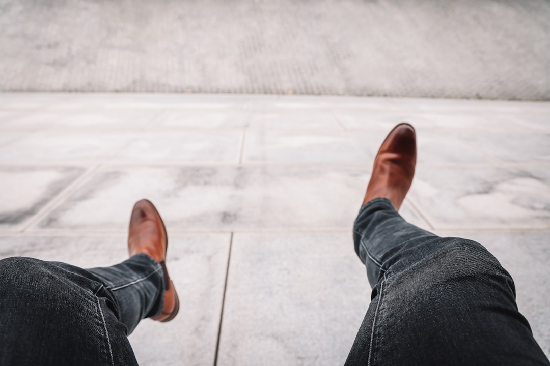 person in blue denim jeans and brown leather shoes