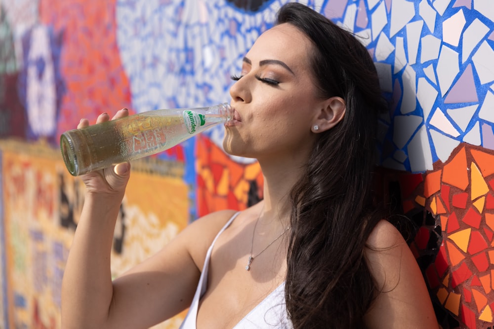 mulher que bebe da garrafa plástica transparente