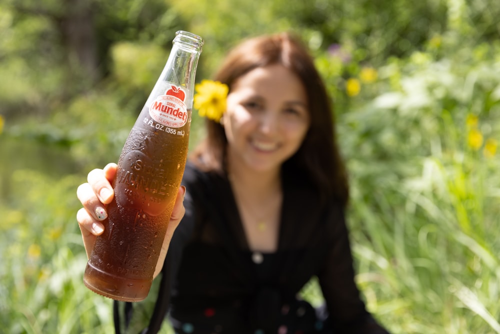 Mujer con camisa negra de manga larga sosteniendo una botella de Coca Cola