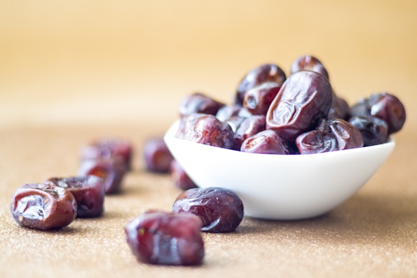 brown round date fruit on white ceramic bowl
