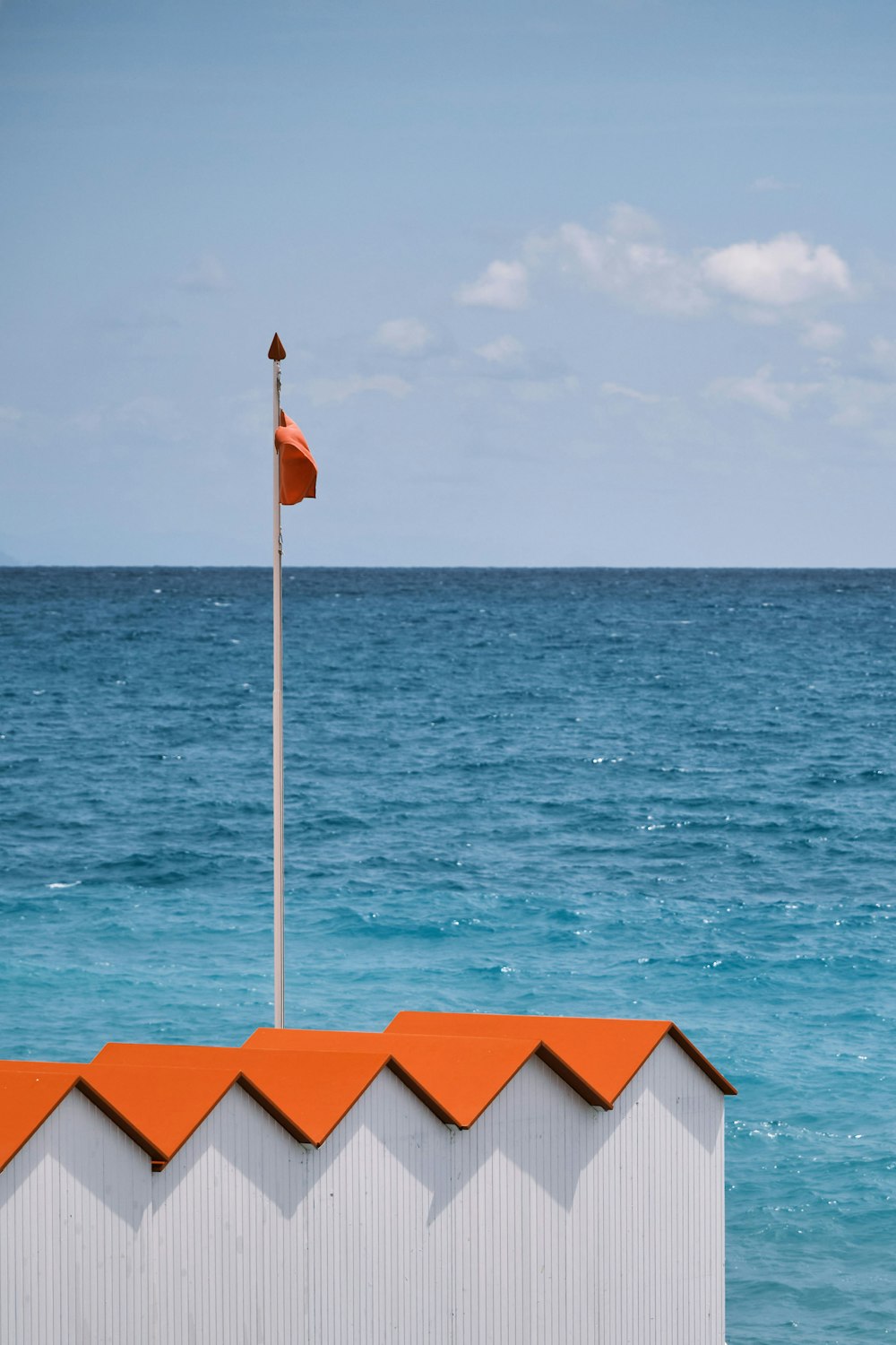 drapeau rouge et blanc sur le mât devant le plan d’eau pendant la journée
