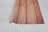 A piece of paper or material with a wooden pattern print is rolled partially on one side, placed on a surface with a woven pattern.