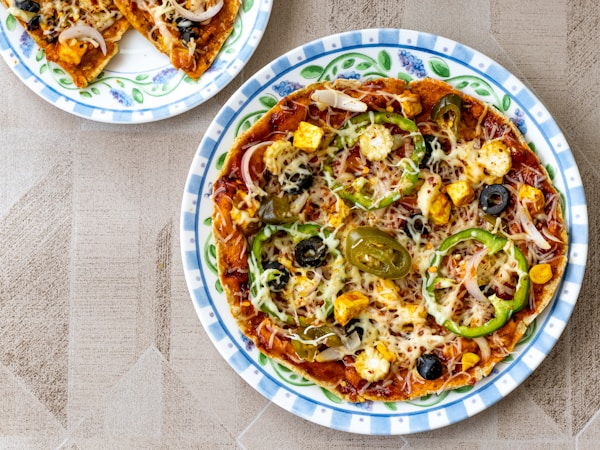 Pizza with green and brown sauce on white ceramic plate