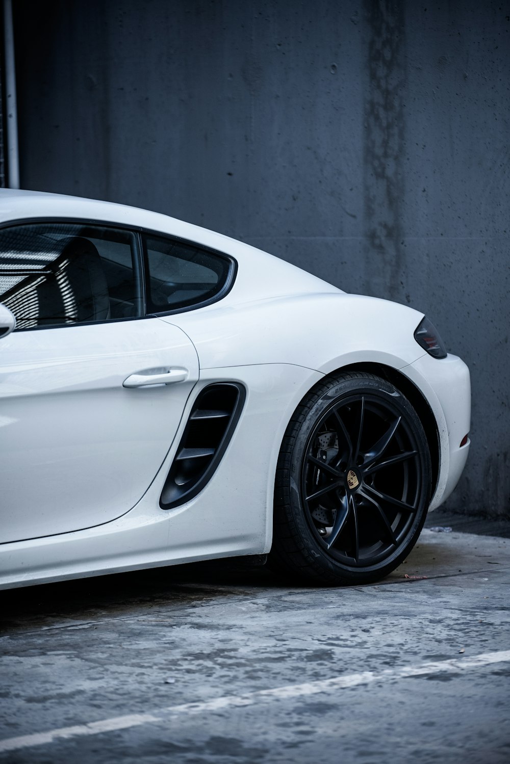 white porsche 911 parked near gray wall