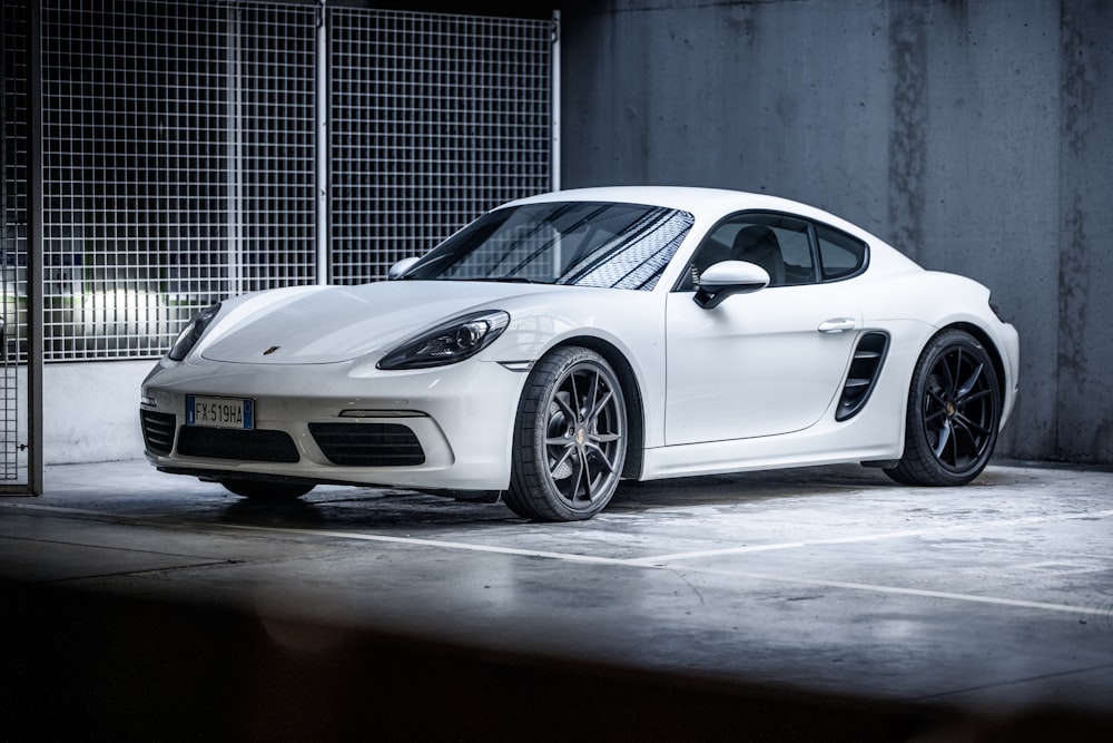 white porsche 911 parked in front of gray building