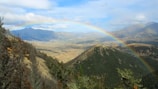 A scenic mountain view with a rainbow arching over a peaceful hiking trail favored by the community.