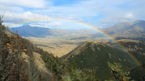 A scenic mountain view with a rainbow arching over a peaceful hiking trail favored by the community.