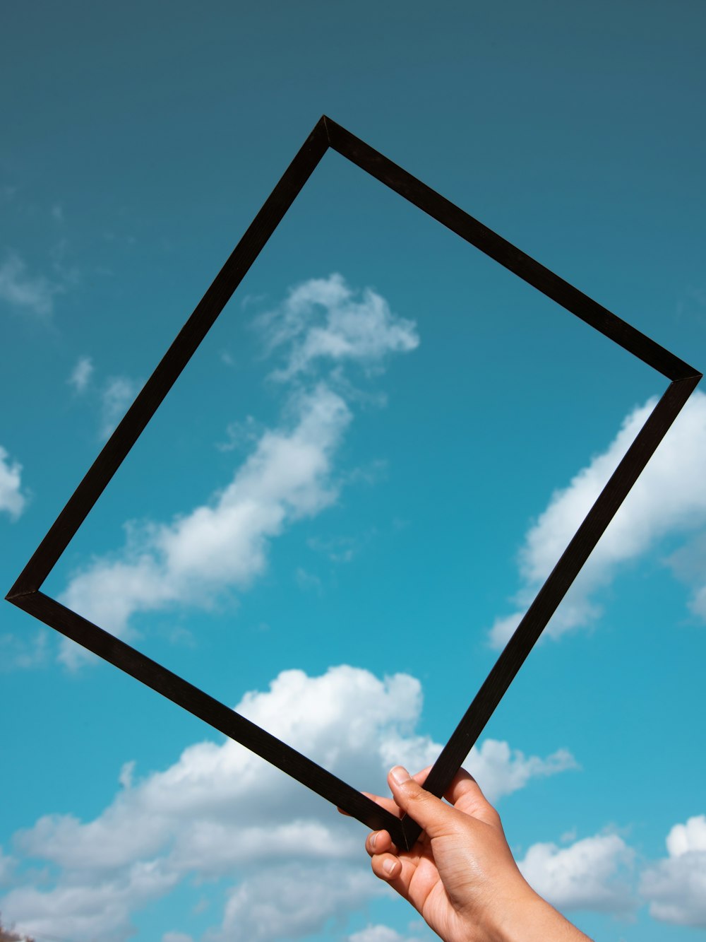 person holding black frame under blue sky during daytime