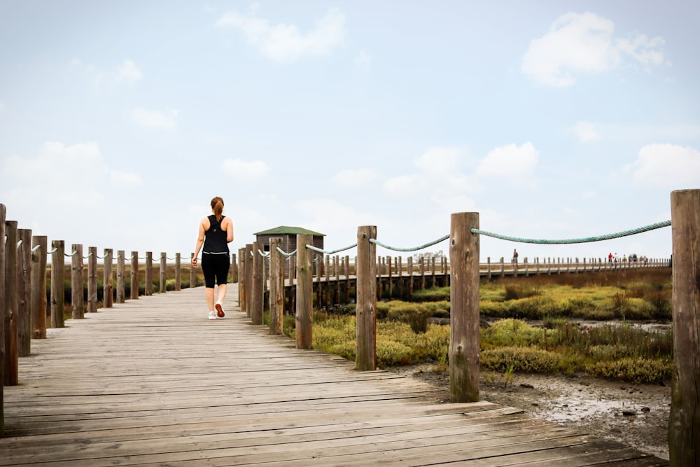 couple walking on wooden bridge during daytime