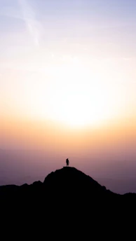 A woman standing strong on a mountain peak at sunrise, symbolizing resilience and new beginnings.
