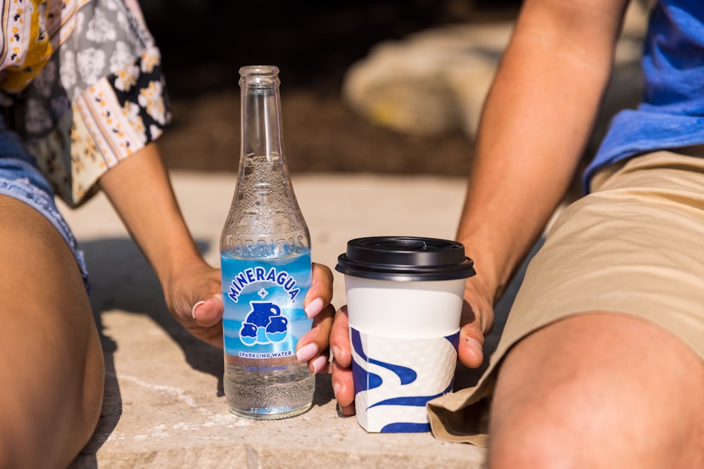 2 person holding white and blue disposable cups