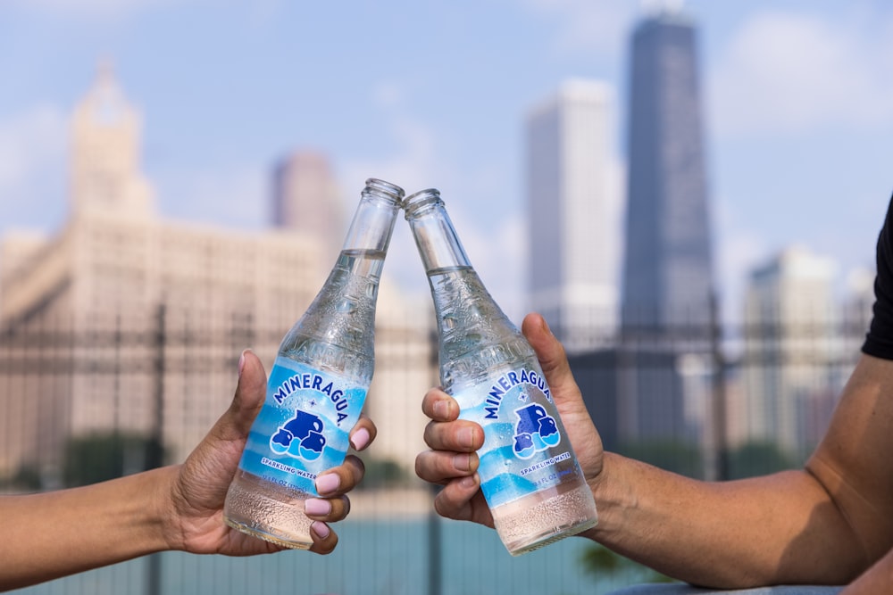 Persona sosteniendo una botella con etiqueta azul y blanca