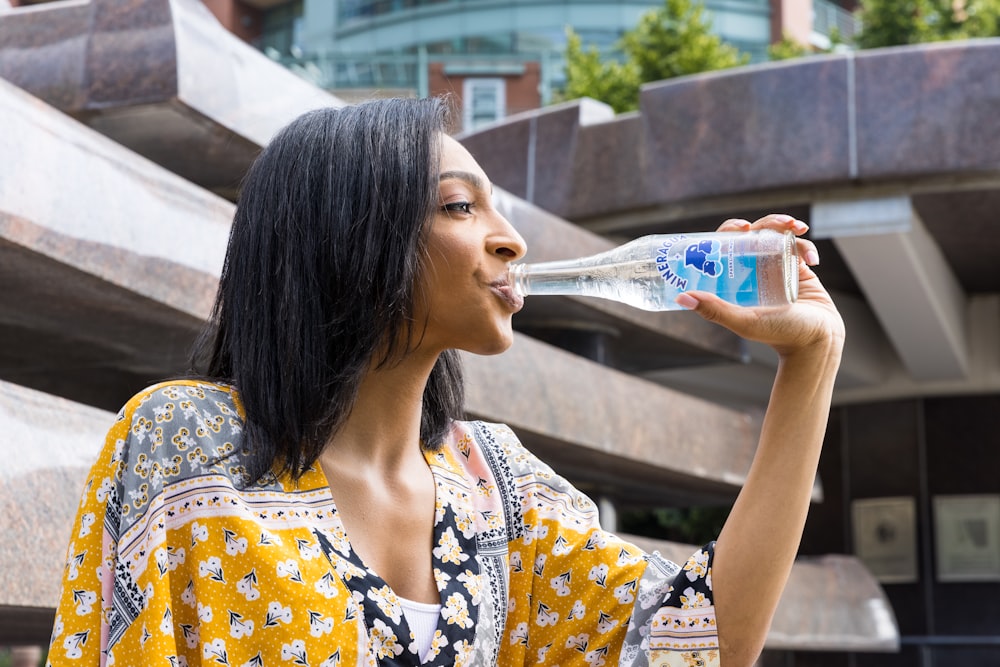 girl in white and blue floral shirt drinking water