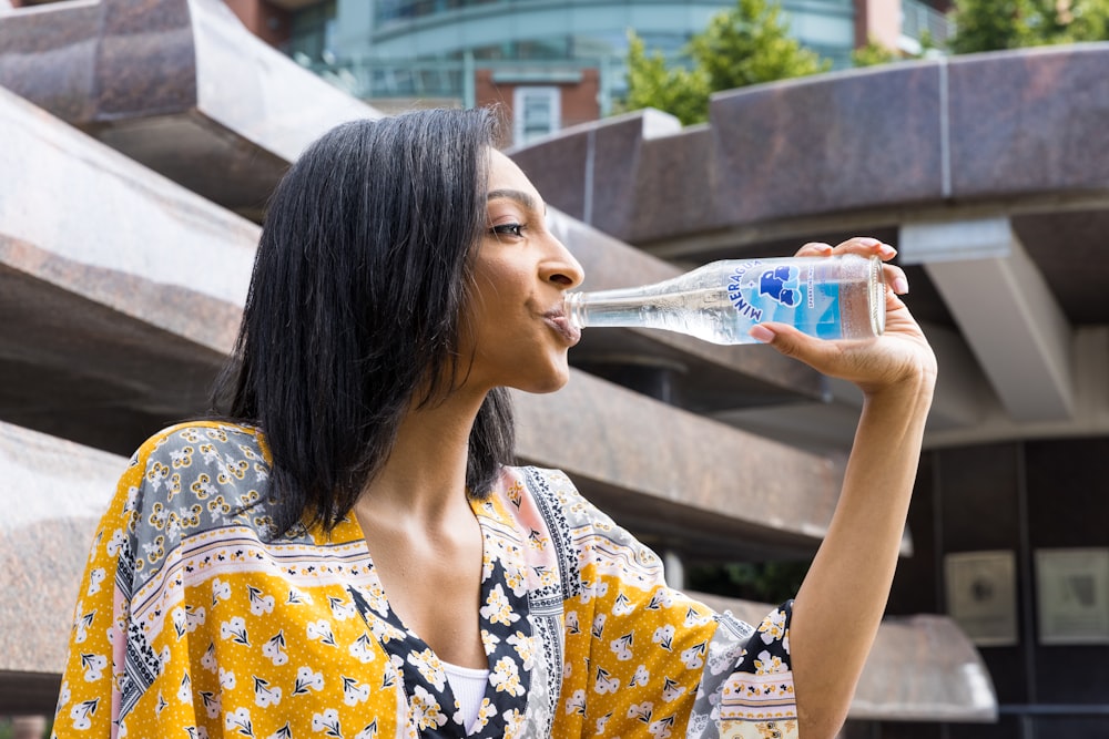 menina na camisa floral branca e azul que bebe água