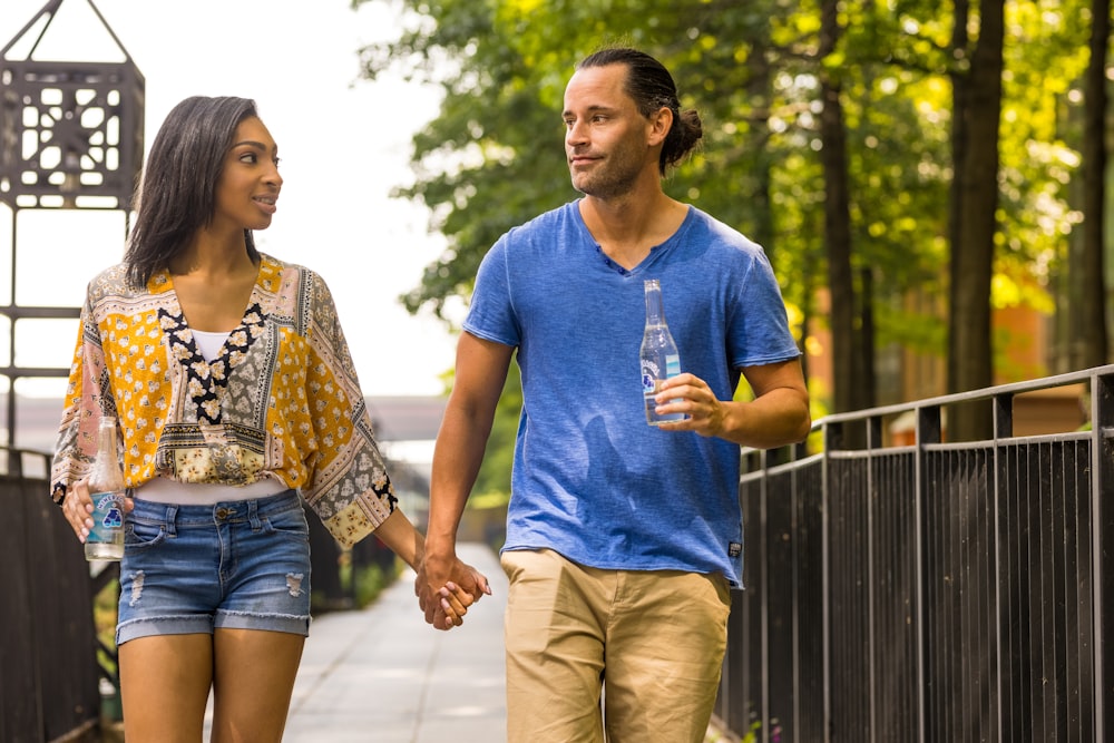 man in blue crew neck t-shirt and brown shorts standing beside woman in white and