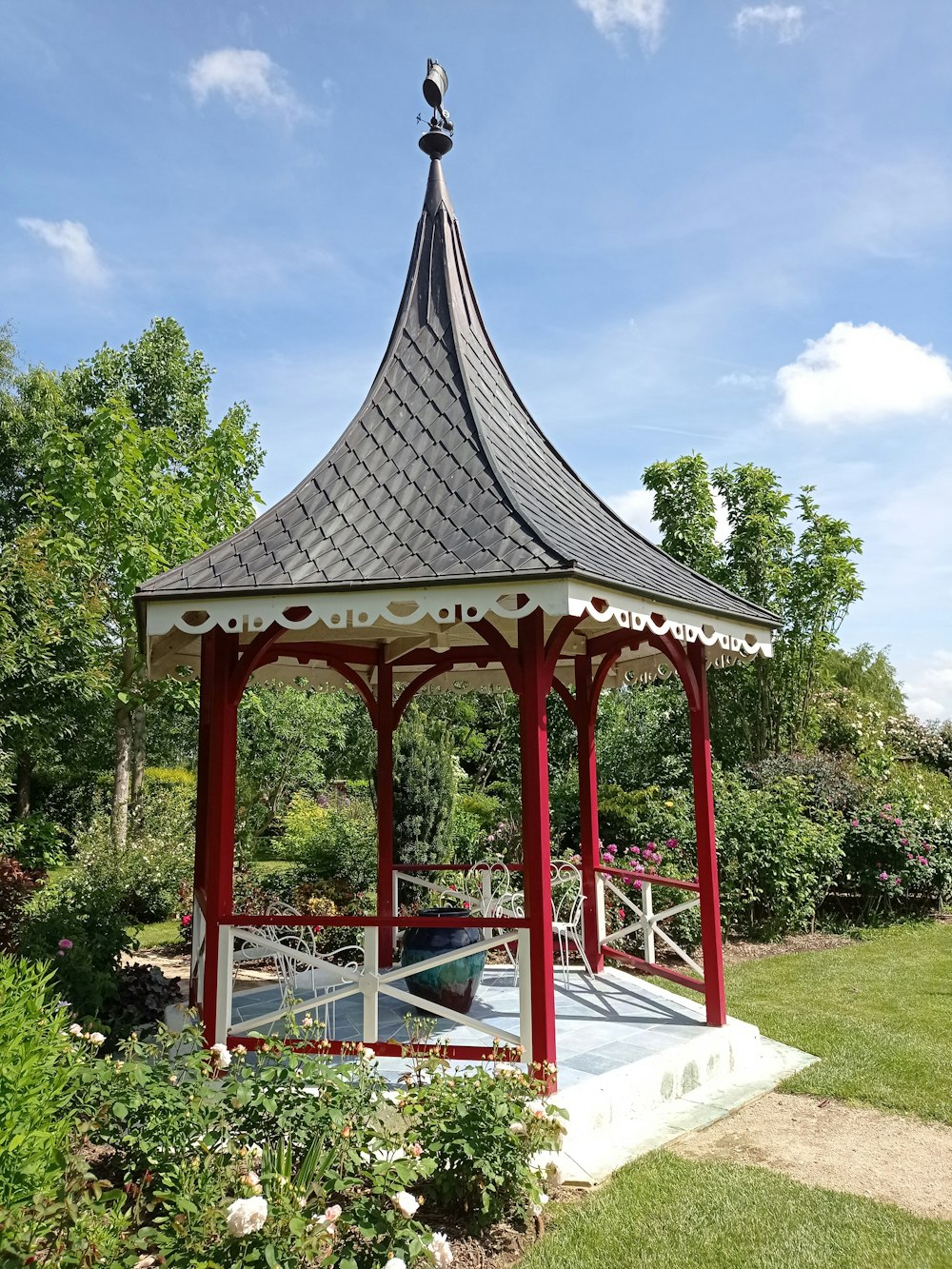 red and gray wooden gazebo surrounded by green trees during daytime